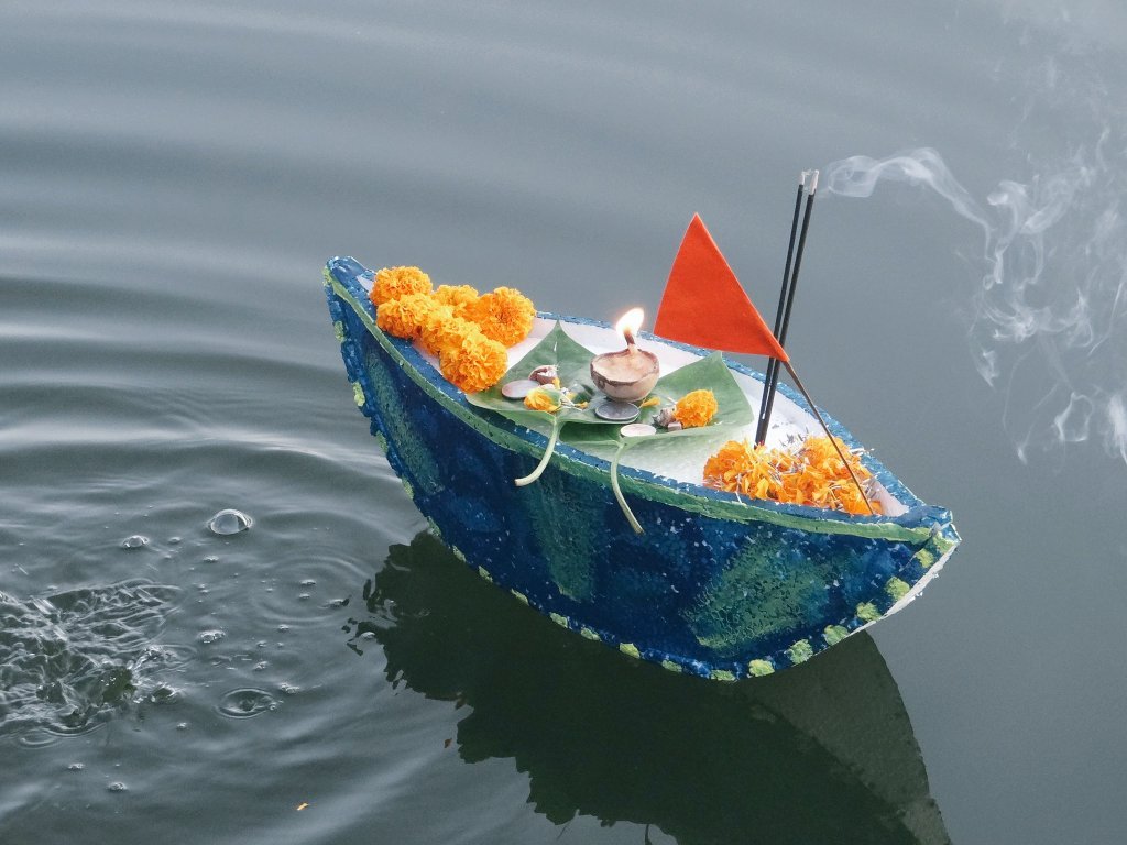 Boito floating in the river with Diya and flower.